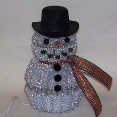 a snowman made out of plastic beads with a black top hat and red ribbon