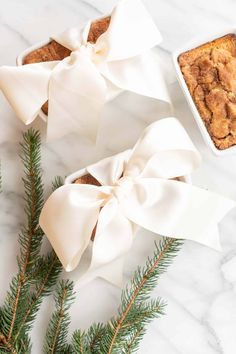 two bow - tied muffins are sitting on a marble table with pine branches