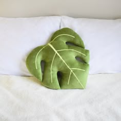 a green leaf shaped pillow sitting on top of a bed