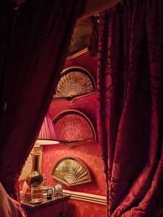 a bedroom with red walls and drapes on the window sill, along with a lamp