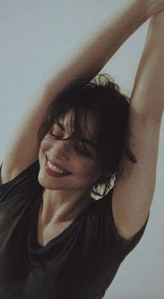 a woman is holding her hair in the air with one hand and smiling at the camera