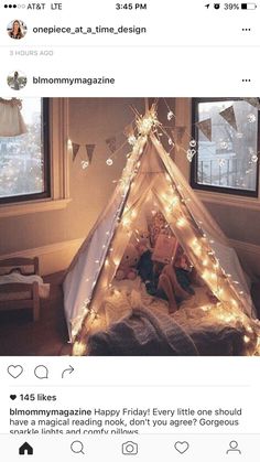 a teepee with fairy lights on it in front of two windows