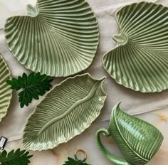 four green leaf shaped dishes sitting on top of a table