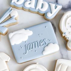 baby cookies and cookie cutters on a marble table with the word james spelled in frosting