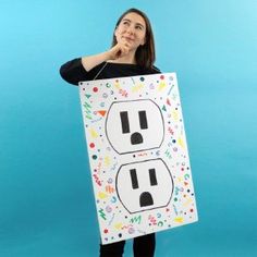 a woman holding up a sign with an electrical outlet on it