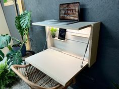 a laptop computer sitting on top of a desk next to a potted green plant