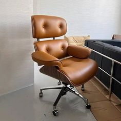 a brown leather chair sitting in front of a black bed next to a white wall