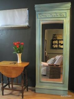 a mirror sitting on top of a wooden table next to a vase filled with flowers