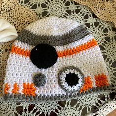 a crocheted hat with an orange and white star wars character on the front