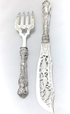 two silver forks and a knife on a white surface