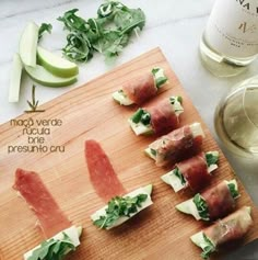 several appetizers are arranged on a cutting board next to a bottle of wine