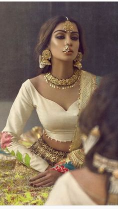 a woman in a white outfit with gold jewelry