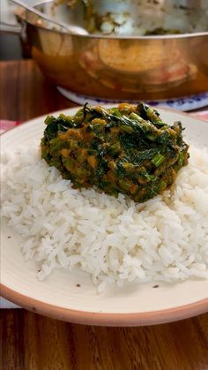 rice and spinach on a plate next to a silver pan