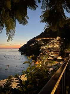 the ocean is lit up at night with boats in the water and trees around it