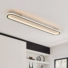 a modern kitchen with white cabinets and black accents, along with an overhead light fixture