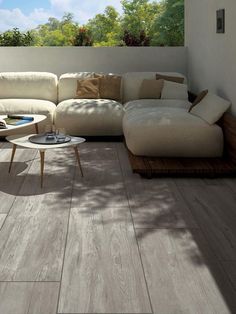 a large white couch sitting on top of a wooden floor next to a table and chair