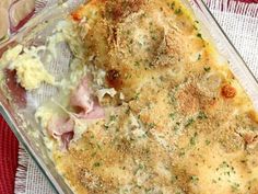 a casserole dish with meat and cheese in it on a red cloth next to a fork