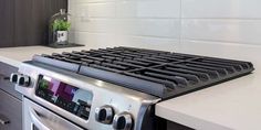 a stainless steel stove top oven in a kitchen with white counter tops and drawers on both sides