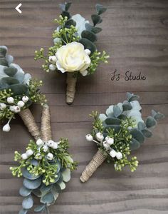 three bouquets with flowers and greenery are arranged on a wooden surface for display