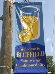 a blue and yellow banner hanging from a wooden pole next to a telephone pole with power lines in the background