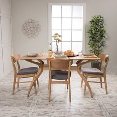 a dining room table with four chairs and a potted plant in the corner next to it