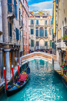 a gondola in the middle of a narrow canal with buildings on either side