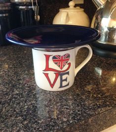 a blue and white coffee cup with the word love painted on it sitting on a counter