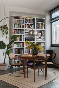 a dining room table and chairs in front of a bookshelf full of books