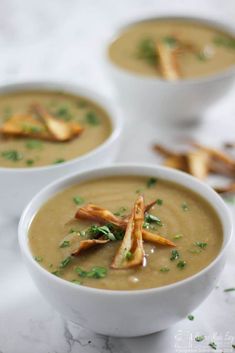 three white bowls filled with soup on top of a table