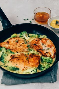 chicken, broccoli and cheese in a skillet next to a glass of beer