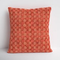 an orange pillow on a white surface with red and brown circles in the middle,