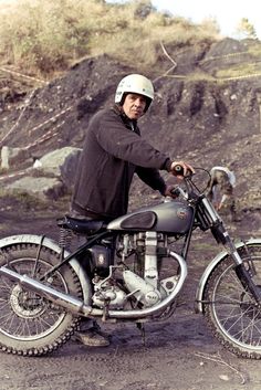 a man sitting on top of a motorcycle in the dirt