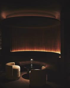 a dimly lit room with two chairs and a table in the center, along with a round coffee table