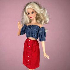 a barbie doll with blonde hair wearing a red skirt and blue top on a pink background