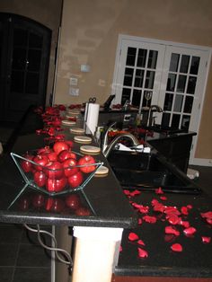 apples are in a bowl on the kitchen counter, with rose petals scattered all over it