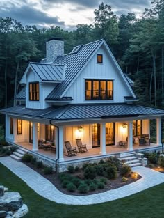 a large white house with lots of windows and lights on the front porch is lit up at night