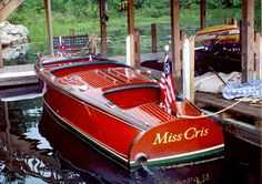 two red boats tied to the dock with an american flag on it's bow