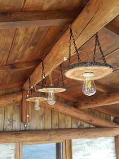 some lights hanging from the ceiling in a wooden room with wood paneling and beams