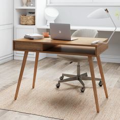 a laptop computer sitting on top of a wooden desk next to a lamp and chair