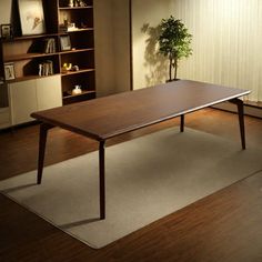 a wooden table sitting on top of a hard wood floor next to a book shelf