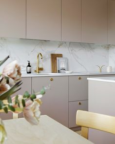 a kitchen with marble counter tops and wooden chairs in front of the sink, along with flowers on the table