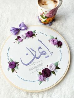 a coffee cup and some flowers on a white surface with the word mamma rama written in arabic