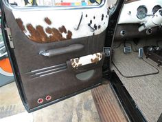 the interior of an old car with cow hide on it's door and dash board