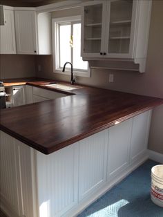 a kitchen with white cabinets and wood counter tops