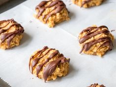 cookies with chocolate drizzled on them sitting on a sheet of parchment paper