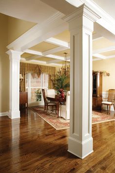 an open living room with wooden floors and white columns