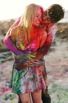 two women covered in colored paint standing next to each other with their arms around each other