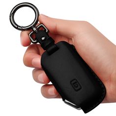 a hand holding a black leather keychain with a metal ring attached to it