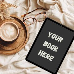 an ipad with a book on it next to a cup of coffee and eyeglasses