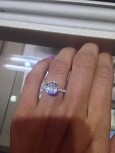 a woman's hand holding an engagement ring with a large diamond on the band